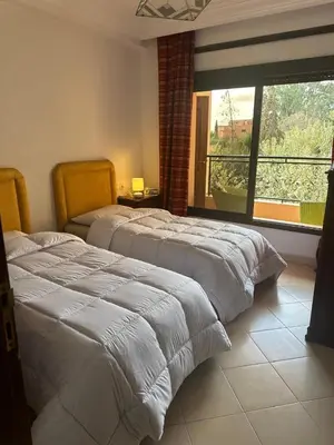 a bedroom with two beds and a large window at Hivernage Bright & Spacious 2-Bedroom Apartment in Marrakech