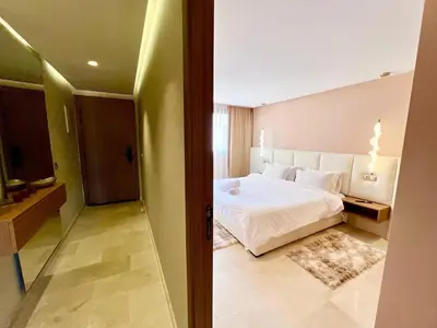 a bedroom with a white bed and a hallway at Modern Gueliz Suite - Balcony Views in Marrakech