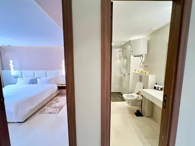 a bedroom with a white bed and a bathroom at Modern Gueliz Suite - Balcony Views in Marrakech
