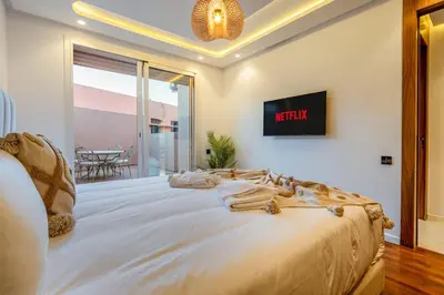 a bedroom with a large bed with a tv on the wall at Le Nahla - Centre - 4 Prs - Terrasse in Marrakech