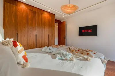 a bedroom with a white bed with a wooden headboard at Le Nahla - Centre - 4 Prs - Terrasse in Marrakech