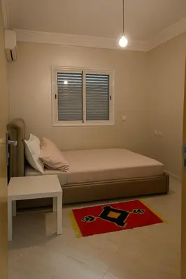 a bedroom with a bed and a window and a rug at Spacious Apartment Near Menara Garden and Airport in Marrakech