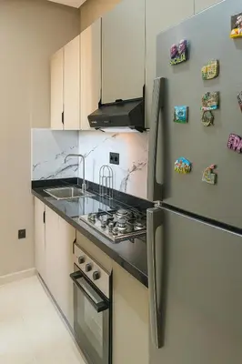 a kitchen with a stove and a refrigerator at Calme & Confort Mabroka - 2 chambre in Marrakech