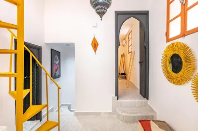 a hallway with white walls and a yellow stairway at Casa Coloré terrace and bohemian charm in Marrakech