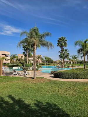 a resort with a swimming pool and palm trees at Luxury apartment in Prestigia Opale in Marrakech