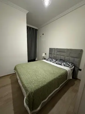 a bedroom with a large bed with a green blanket at 3wina immobilier in Marrakech