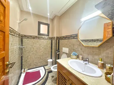 a bathroom with a sink and a toilet and a mirror at Palmeraie, Appart chic Suite & Accès à 3 Piscines in Dar Caïd Layadi