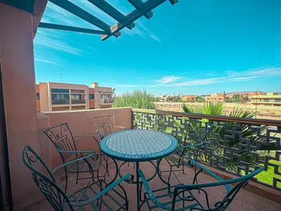 a patio with a table and chairs on a balcony at Palmeraie, Appart chic Suite & Accès à 3 Piscines in Dar Caïd Layadi