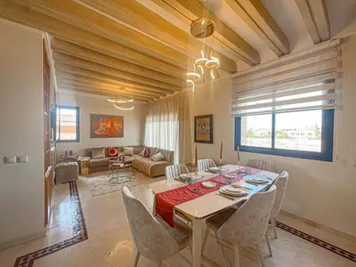 a dining room with a table and chairs and a living room at Palmeraie, Appart chic Suite & Accès à 3 Piscines in Dar Caïd Layadi