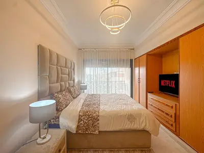 a bedroom with a large bed and a television at Palmeraie, Appart chic Suite & Accès à 3 Piscines in Dar Caïd Layadi