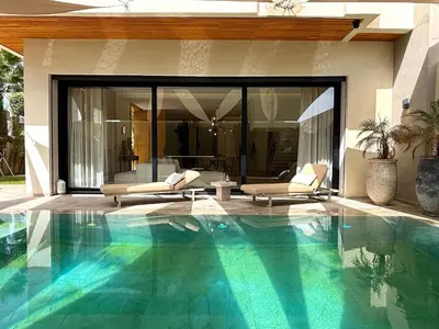 a swimming pool with two chairs and a house at Palais Oyena in Marrakech