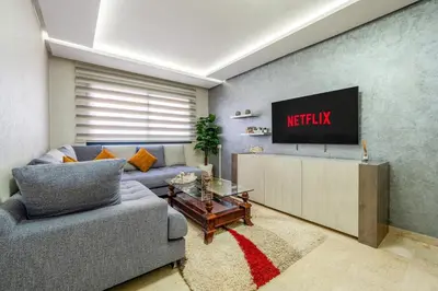 a living room with a couch and a tv at Luxe City Escape 2BR Pool in Marrakech