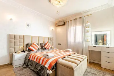 a bedroom with a large bed with an orange and white blanket at Princess in Marrakech