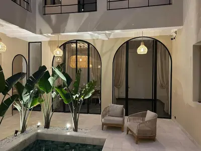 a lobby with a pool and two chairs and plants at Riad A l'Ombre du Palais in Marrakech