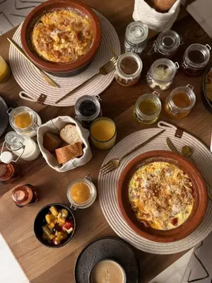 a wooden table with two plates of food and bread at Riad A l'Ombre du Palais in Marrakech