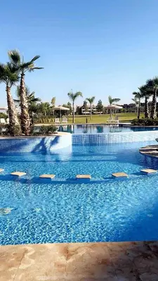 a large swimming pool with palm trees in the background at Luxury Prestigia Golf City jade in Marrakech