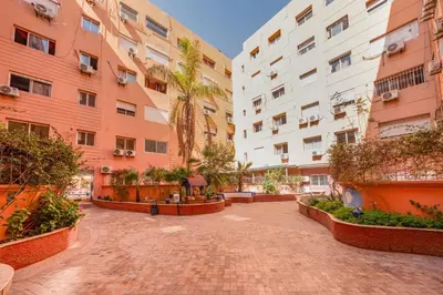 an empty courtyard with two tall buildings and trees at Luxury 2BR Apt in Gueliz, Pools, Parking,Elevator in Marrakech