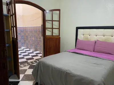 a bedroom with a bed and a door to a bathroom at Garden View Comfort Apartment in Marrakech