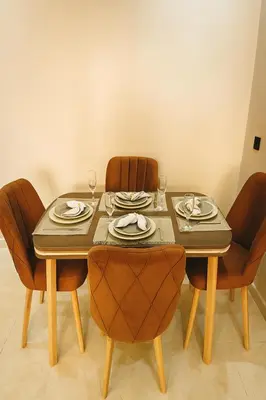 a dining room table with chairs and plates and wine glasses at Appartement Confort & Sérénité Mabroka Marrakech in Marrakech