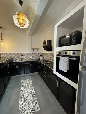 a large kitchen with black cabinets and a sink at Villa Selma piscine privée sans vis à vis 9 min du centre in Marrakech