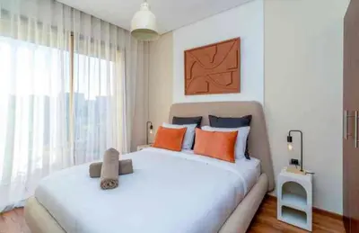 a bedroom with a large white bed with orange pillows at Appartement luxe avec vue imprenable sur le golf in Marrakech