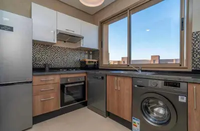 a kitchen with a washing machine and a window at Appartement luxe avec vue imprenable sur le golf in Marrakech