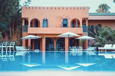 a resort with a swimming pool with chairs and umbrellas at La Vie En Rose - Horses & Dogs House in Marrakech