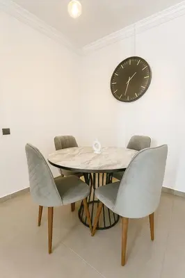 a dining room table and chairs with a clock on the wall at Cozy Appartement avec jacuzzi chauffant in Marrakech