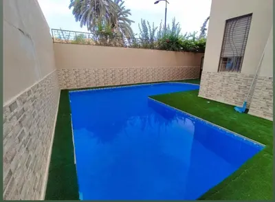 a blue swimming pool in a house with green grass at Villa zinaya in Marrakech