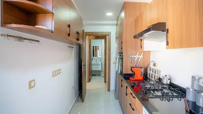 a kitchen with wooden cabinets and a stove top oven at Bel appart vue piscine dans résidence sécurisée in Marrakech