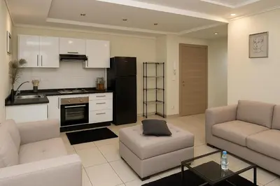 a kitchen and living room with a couch and a table at Superbe Duplex moderne à Izdihar in Marrakech