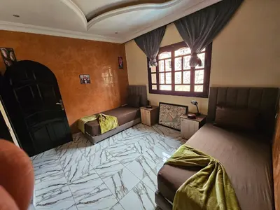 a bedroom with two beds and a tiled floor at la villa cozy in Marrakech