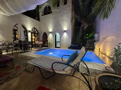 a swimming pool with a bench and a chair next to it at Riad Wael in Marrakech