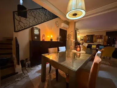 a dining room with a table and a living room at Riad Wael in Marrakech