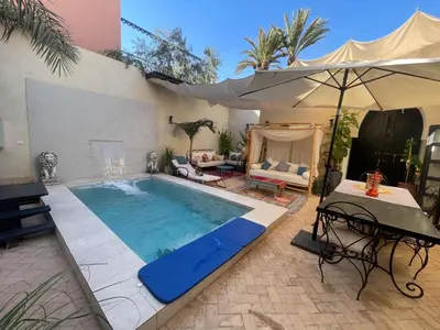 a swimming pool in a patio with an umbrella at Riad Wael in Marrakech