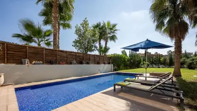 a swimming pool with a table and an umbrella at Villa de luxe in Marrakech