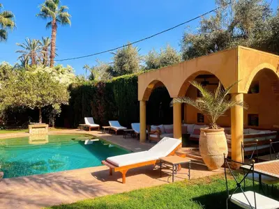 a backyard with a swimming pool with chairs and avisor at Maison Yves st Laurent - Piscine in Marrakech