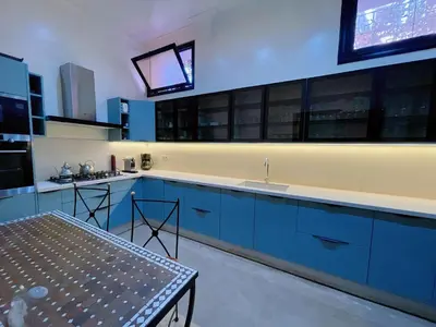 a kitchen with blue cabinets and a sink and a table at Maison Yves st Laurent - Piscine in Marrakech