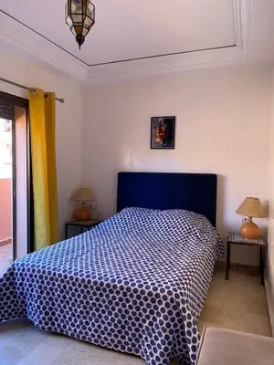 a bedroom with a bed with a blue and white comforter at Appartement en plein cœur de Marrakech in Marrakech