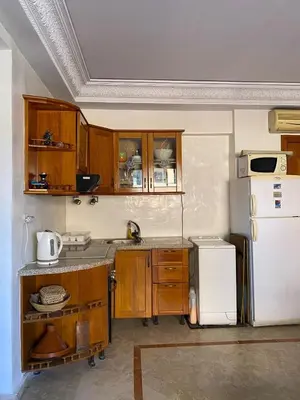 a kitchen with wooden cabinets and a white refrigerator at Appartement en plein cœur de Marrakech in Marrakech