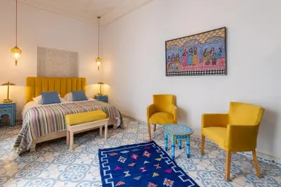 a bedroom with a bed and two chairs and a rug at Palais el Abbassia in Marrakech