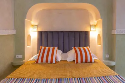 a bedroom with a large bed with two orange and white pillows at Palais el Abbassia in Marrakech
