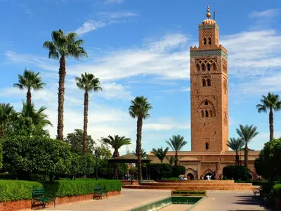 a clock tower in front of a building with palm trees at Arabian Riad Marrakech in Marrakech