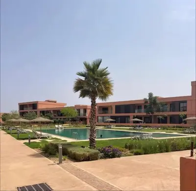 a palm tree in front of a building with a pool at Domaine Noria - Modern apartment, quiet & 4 pools in Marrakech