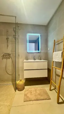 a bathroom with a sink and a glass shower at Domaine Noria - Modern apartment, quiet & 4 pools in Marrakech