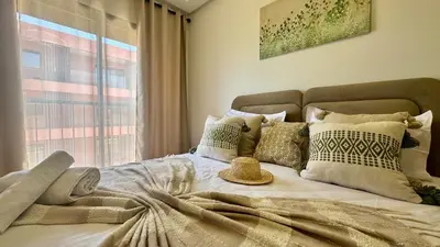 a bedroom with a bed with pillows and a window at Domaine Noria - Modern apartment, quiet & 4 pools in Marrakech