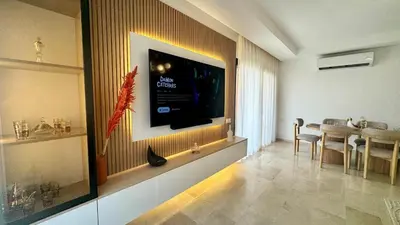 a living room with a dining table and a television on a wall at Domaine Noria - Modern apartment, quiet & 4 pools in Marrakech