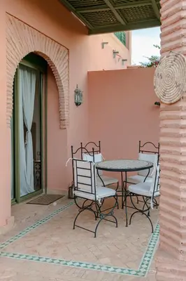 a patio with a table and chairs next to a wall at Marrakech Palmeraie 2, 2-bedroom appartment, G1 , swimming pool residence, in Marrakech