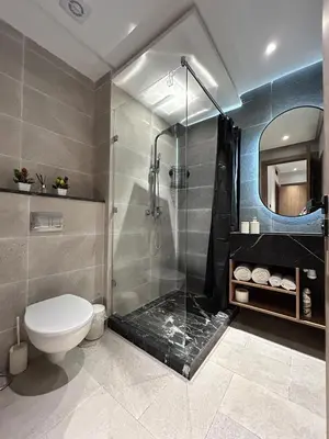 a bathroom with a toilet and a glass shower at Appartement Moderne - Accès Piscines et Fitness in Marrakech
