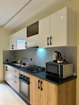 a kitchen with white cabinets and a black counter top at Appartement Moderne - Accès Piscines et Fitness in Marrakech